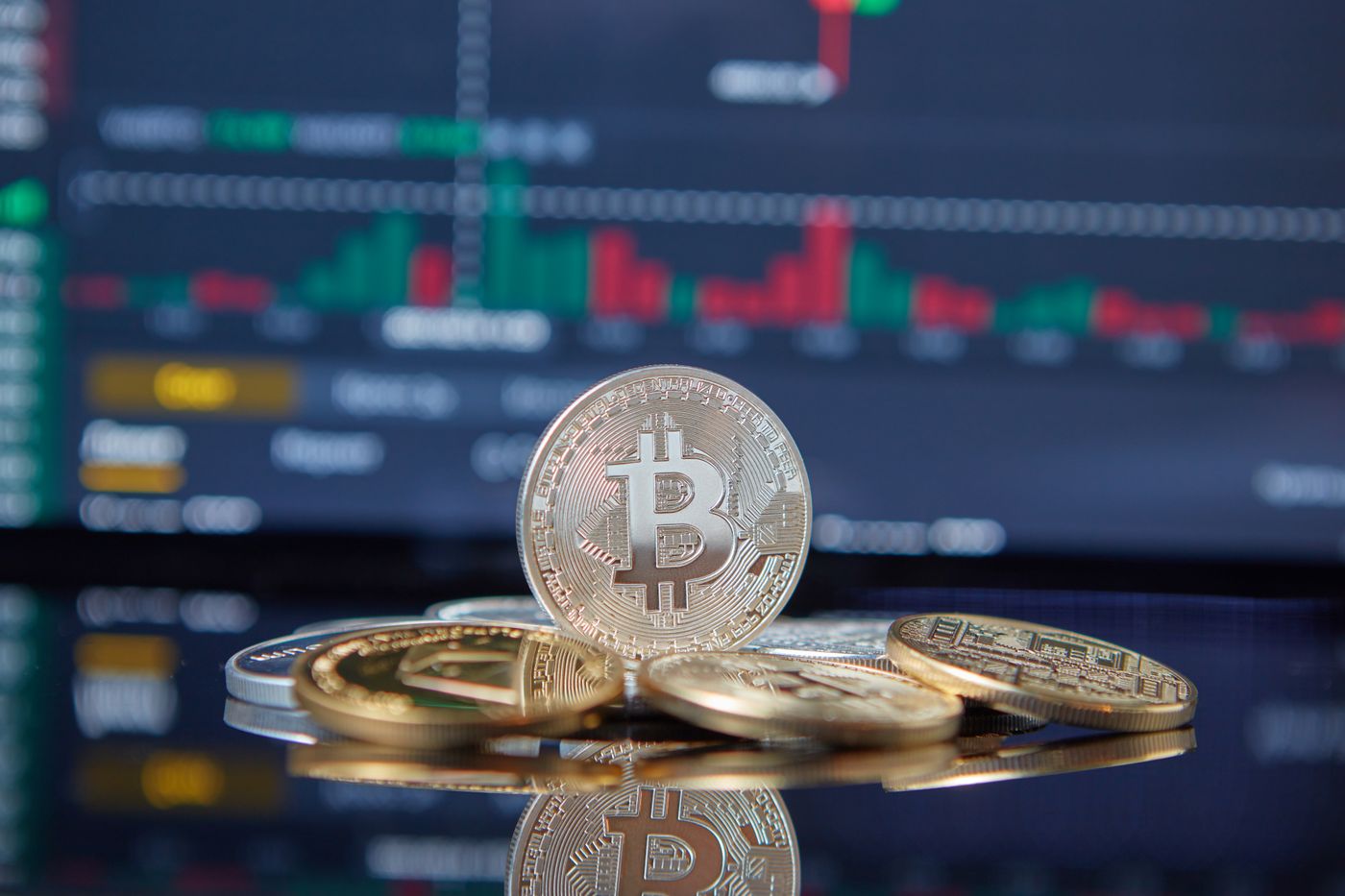 Symbolmünzen für Bitcoin vor einem Bildschirm